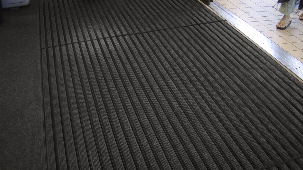 Image of Nuway Grid Black Anodised barrier matting installed in a doorway
