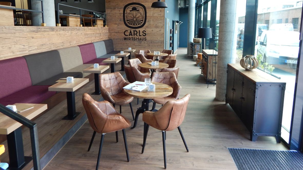 Carls-Wirtshaus Karlsruhe Rastraum mit Tischen und Stühlen – Forbo Allura Wood 