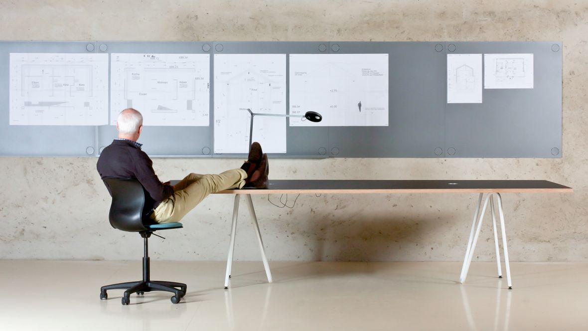 Möbelprogramm Franz Faust Linoleum Mann auf Bürostuhl mit Füßen auf einem Tisch – Forbo Furniture Linoleum