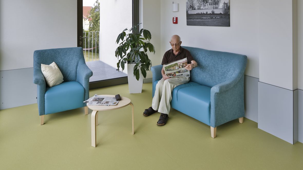 Wohnen und Pflegen im Sonnengarten Rentner auf blauer Sitzgarnitur - Forbo Marmoleum Piano