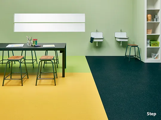 Step safety vinyl in green, yellow and black in a childrens classroom beneath a black table and stools