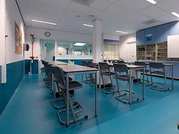 Classroom with blue flooring and high desks
