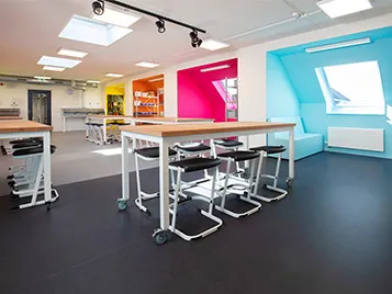 Classroom with black and grey flooring with high desks