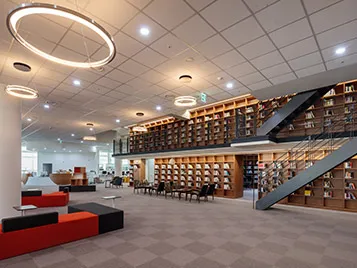 Multi-floor library area with grey flooring, red benches and brown book shelves